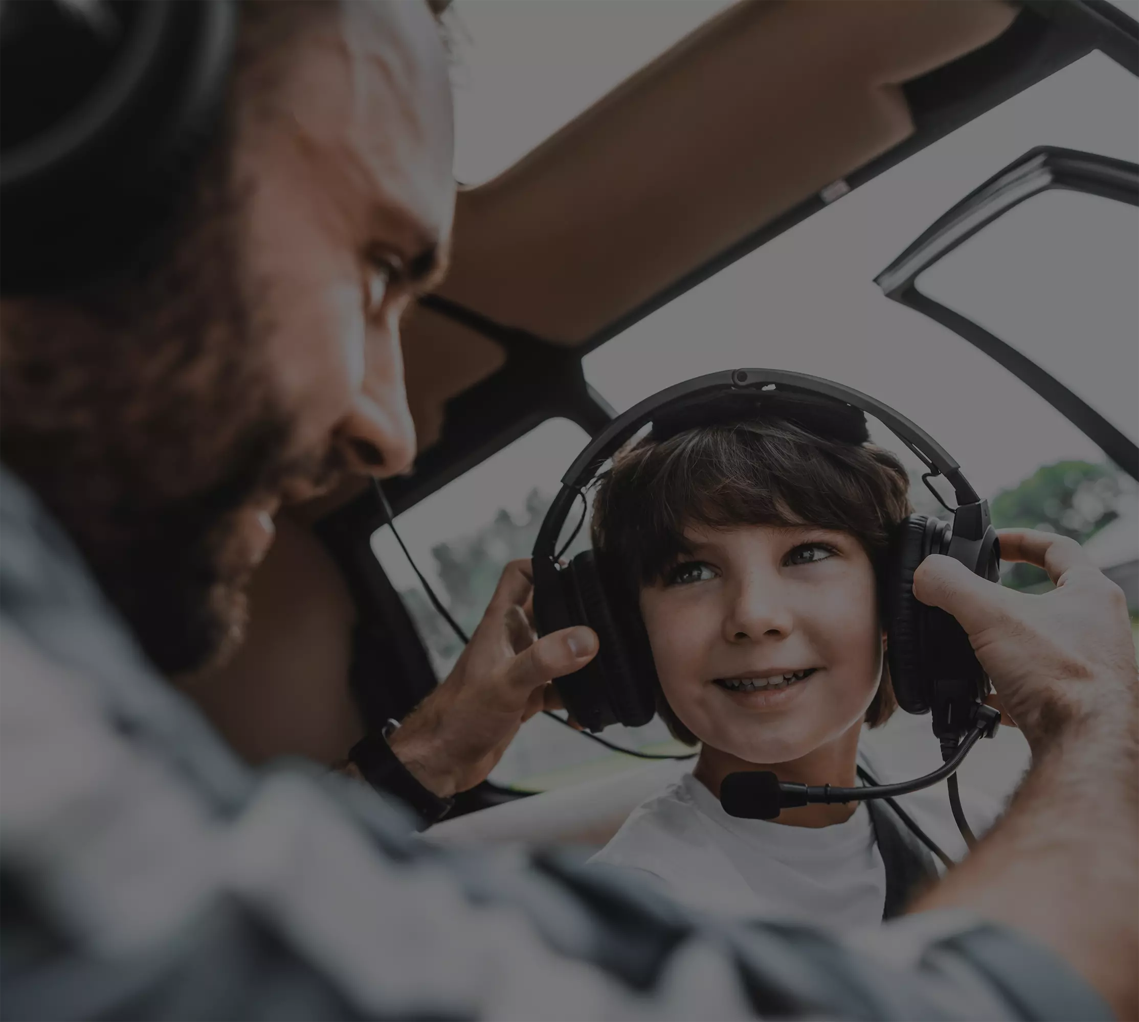 man putting headphones on child in a helicopter