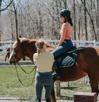 woman standing next to girl on horse