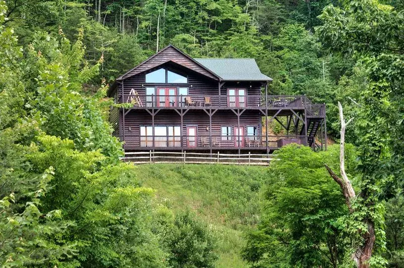 dark two-story wood cabin with upper and lower porches